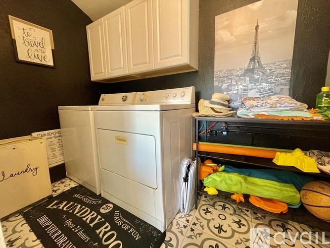 A laundry room with a washer and dryer, a sign that says "To Travel or Not to Travel" and a picture of the Eiffel Tower on the wall.