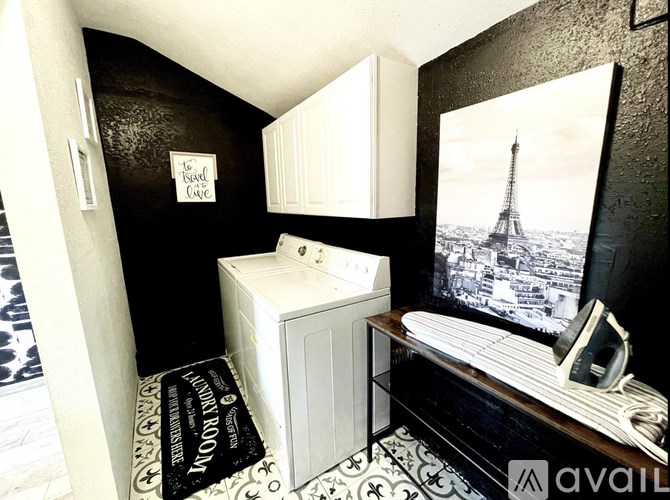 A black and white bathroom with a washing machine and ironing board.