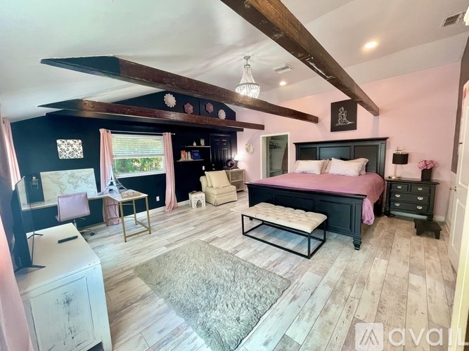 A bedroom with a pink bed and wooden beams on the ceiling.