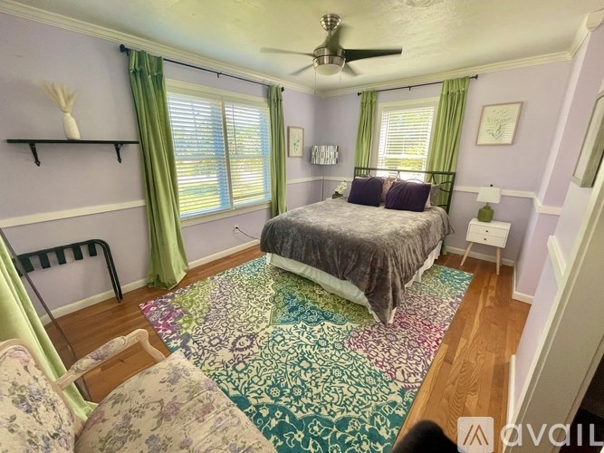 A bedroom with a bed, a ceiling fan, and a rug on the floor.