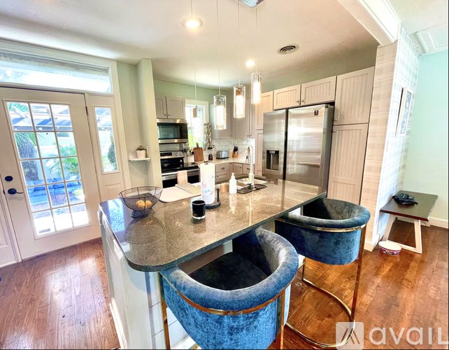 A kitchen with a granite countertop and blue chairs.