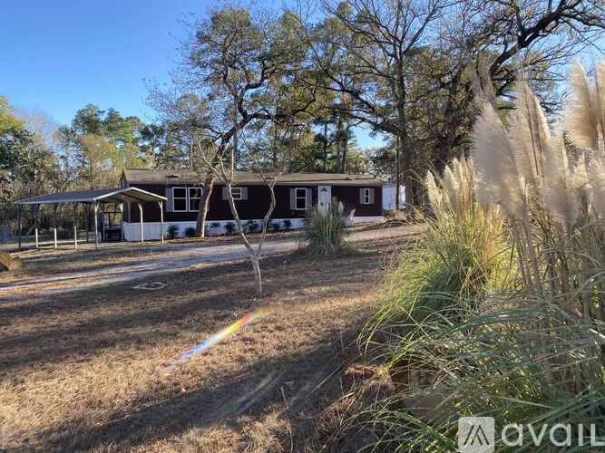A house is surrounded by dry grass and trees.