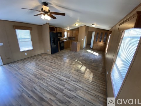 A spacious room with wooden flooring and a ceiling fan.