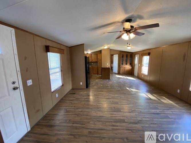 A spacious room with wooden floors and a ceiling fan.
