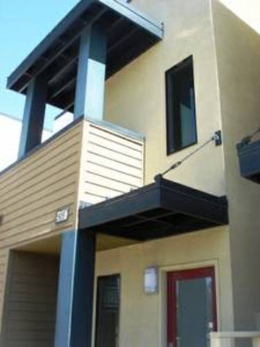 A modern house with a red door and a balcony.