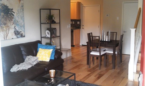 A black couch with a yellow pillow sits in a living room.