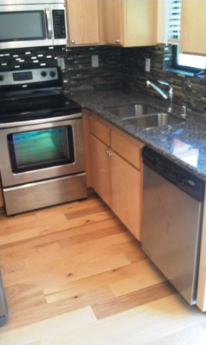A kitchen with a black granite counter top and wooden cabinets.