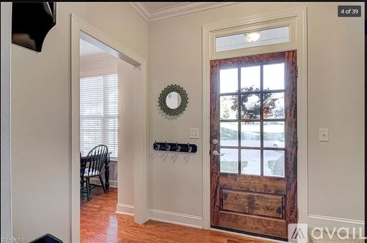 A room with a wooden door and a wreath on the window.
