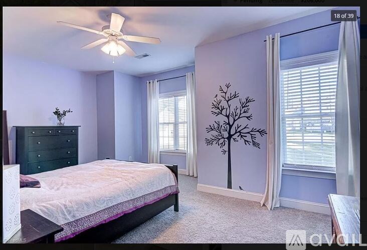 A bedroom with a bed, dresser, and window with a tree decal.