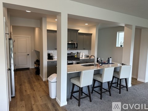 A kitchen with a white countertop and a sink with four chairs around it.