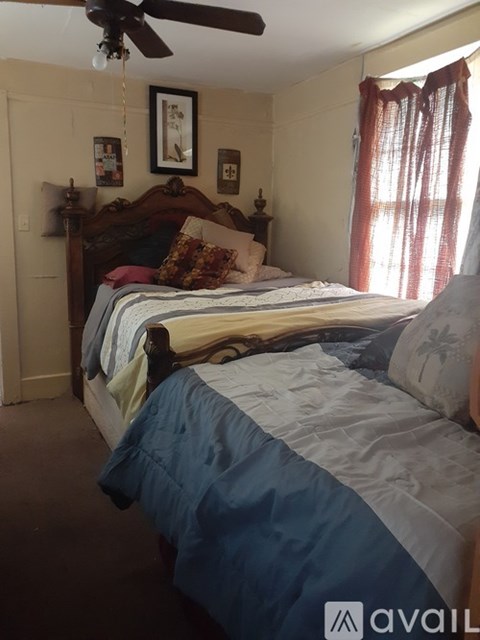 A bedroom with a bed, pillows, and a ceiling fan.
