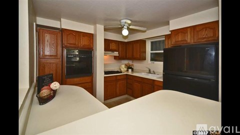 A kitchen with wooden cabinets and a black refrigerator.