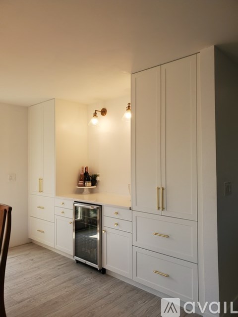 A kitchen with white cabinets and a stainless steel refrigerator.
