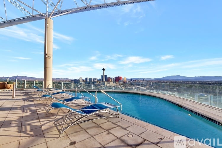 A pool area with chairs and a view of the city.
