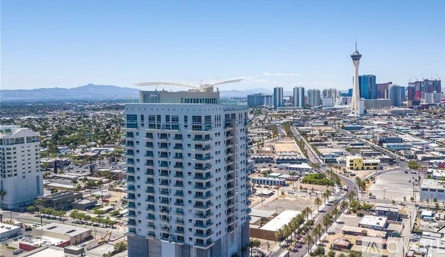 A tall white building stands in the foreground of a cityscape.