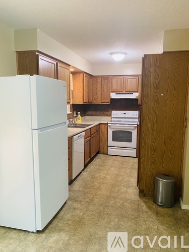 A kitchen with white appliances and wooden cabinets.