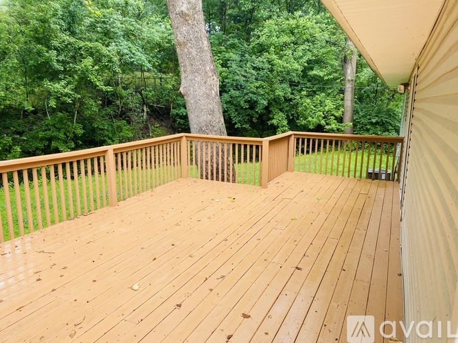A wooden deck with a railing and trees in the background.