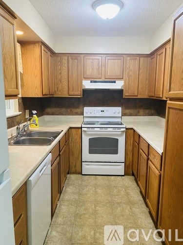 A kitchen with wooden cabinets and a white stove top oven.