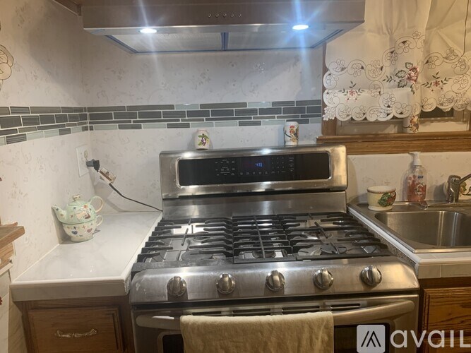 A stainless steel gas stove in a kitchen with a white tile backsplash.
