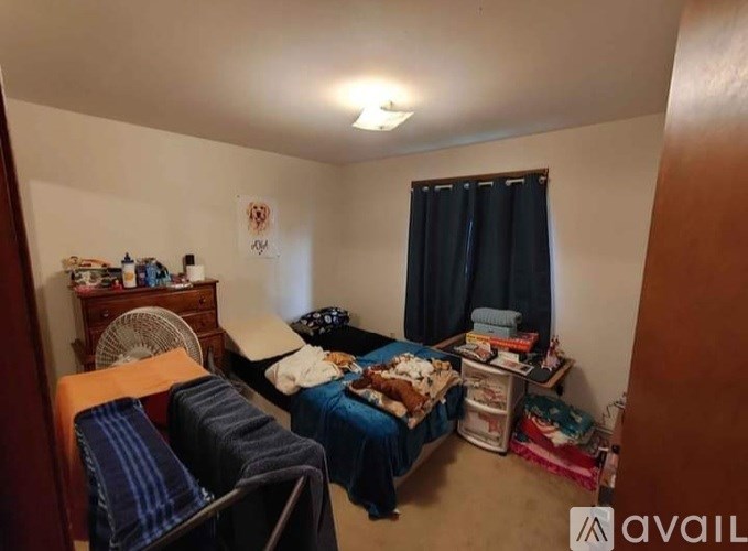 A bedroom with a bed, a chair, and a fan.