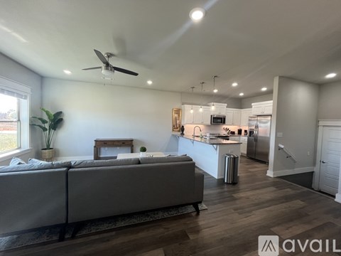 A modern living room with a grey sofa and a kitchen in the background.