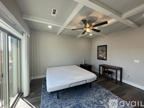 A bedroom with a bed, a table, and a ceiling fan.