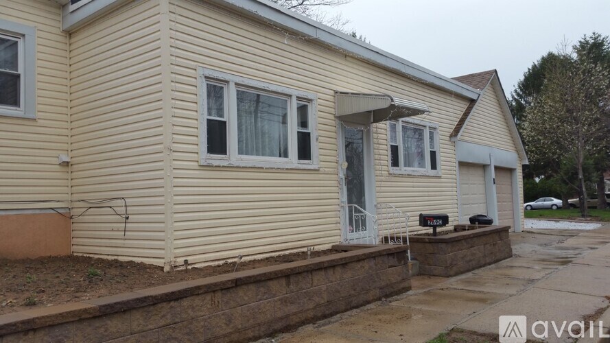 A house with a beige siding and a white door is available for rent.