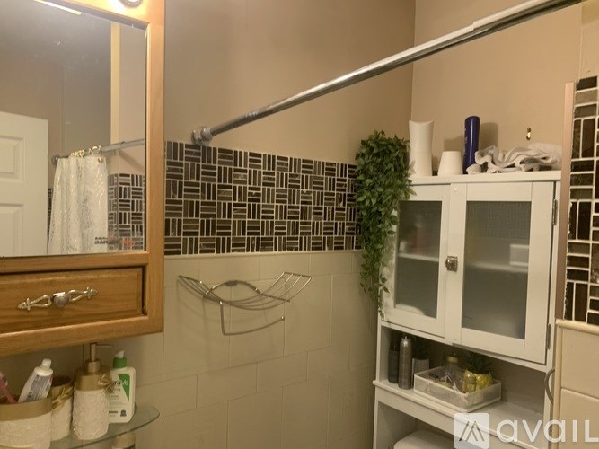 A bathroom with a white cabinet and a mirror above it.