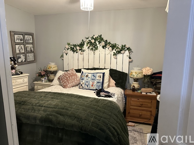 A bedroom with a white bed and a green comforter.