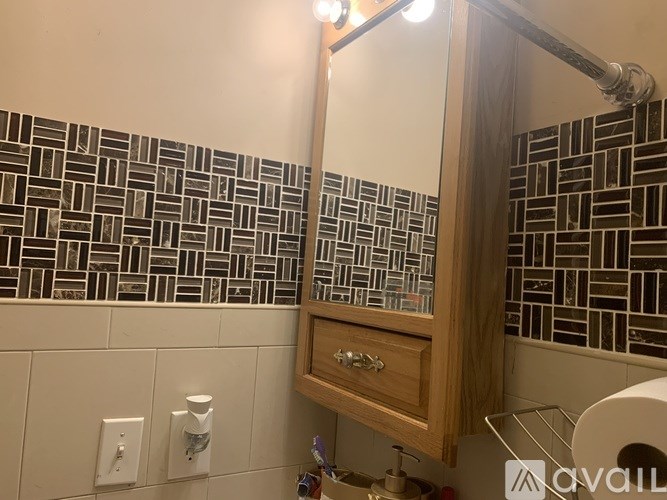 A bathroom with a mirror and a tiled wall.