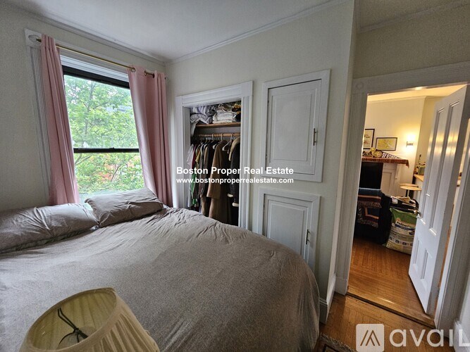 A bedroom with a large bed and a window with pink curtains.