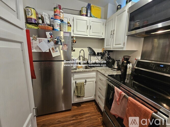 A kitchen with a stainless steel refrigerator and wooden floors.