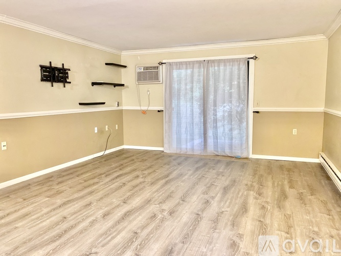 A room with wooden flooring and a window with curtains.