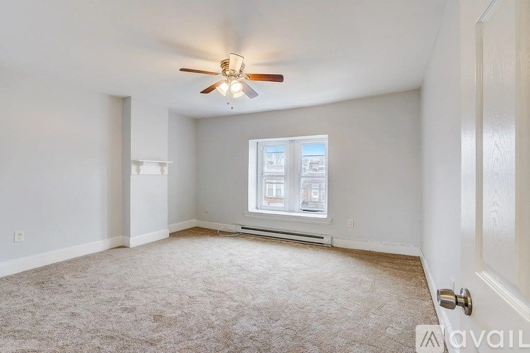 A room with a ceiling fan and a window with a view of buildings outside.