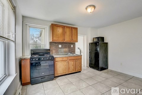 A kitchen with a black refrigerator and wooden cabinets.