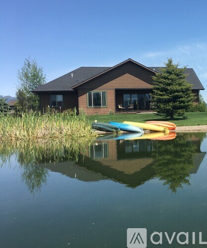 A house with a brown roof and a pond in front of it.