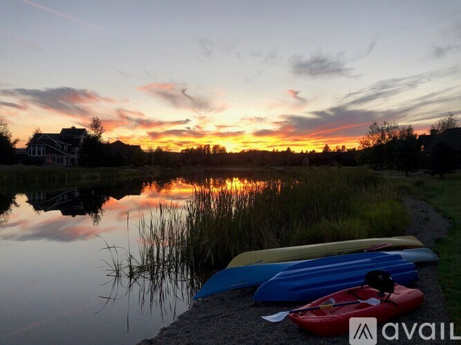 Canoes are lined up on the shore of a lake at sunset.