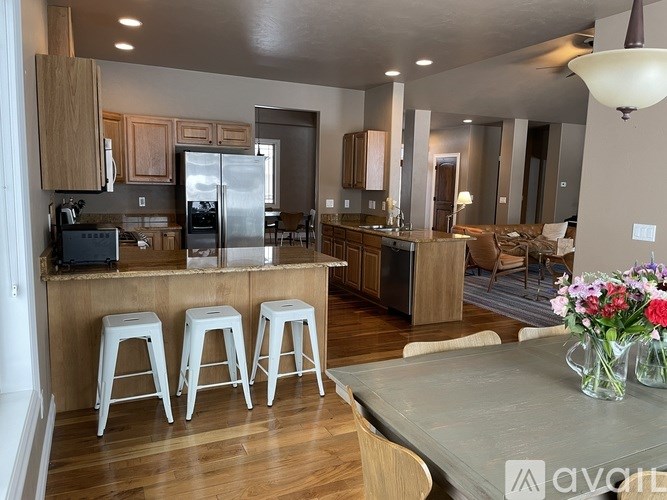 A kitchen with a refrigerator, stove, and bar stools.