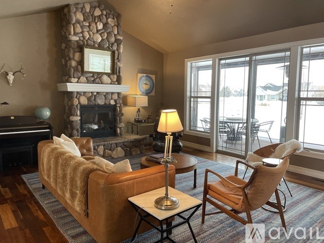 A living room with a stone fireplace and a brown couch.