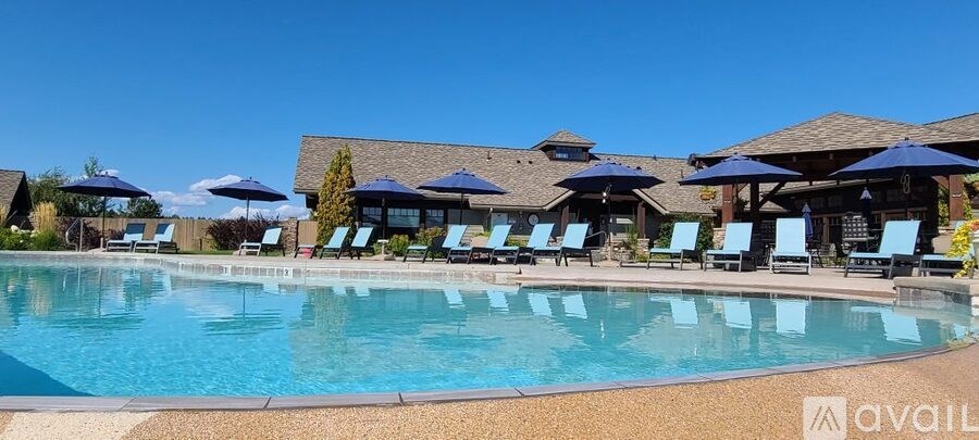 A large swimming pool surrounded by blue lounge chairs and umbrellas.