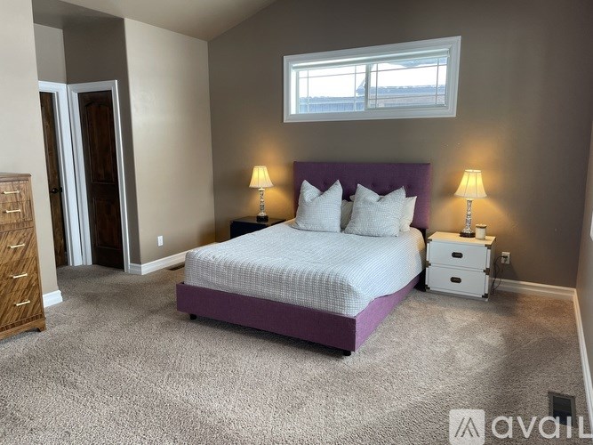 A bedroom with a bed, nightstands, and lamps.