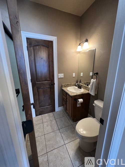 A bathroom with a toilet, sink, and mirror.