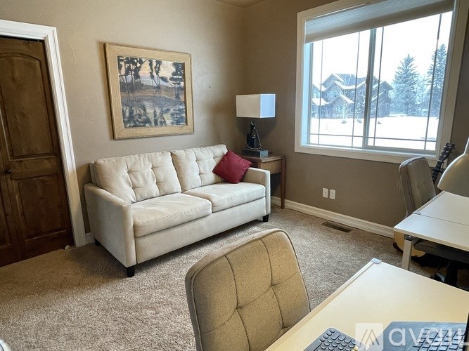 A living room with a white couch and a painting on the wall.