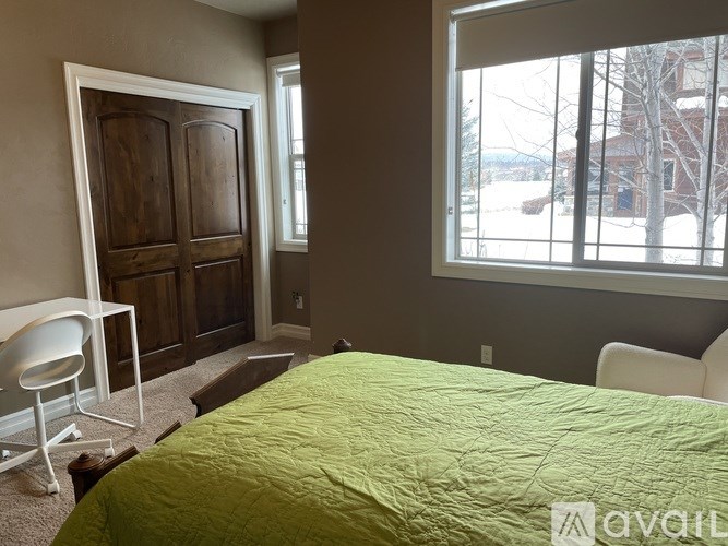 A bedroom with a bed, chair, and a large window.