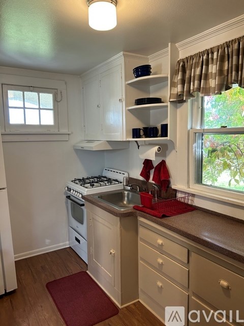 A kitchen with a white stove and a window with a curtain.