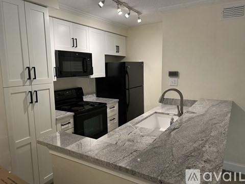 A kitchen with granite countertops and black appliances.