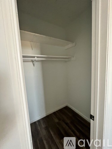 A white closet with a shelf and a door.
