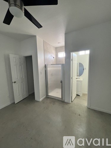 A room with a ceiling fan and a door on the left.