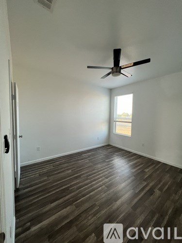A room with a ceiling fan and wooden flooring.