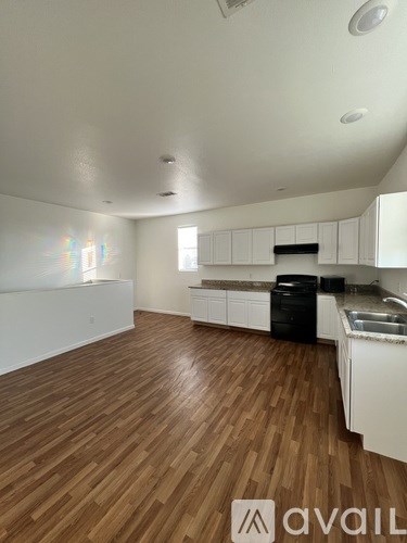 A kitchen with white cabinets and a wooden floor.